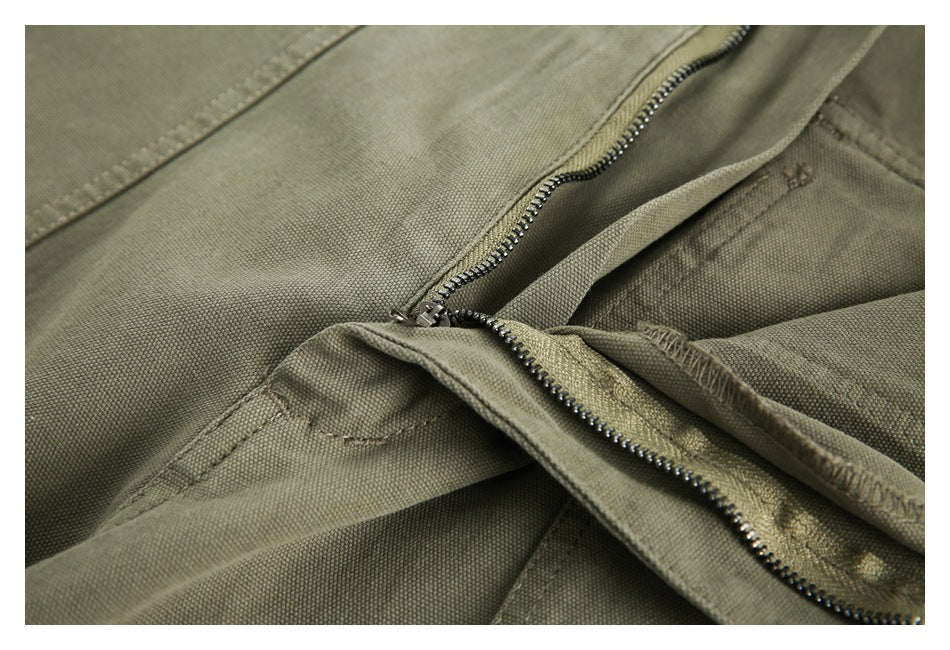 Close-up of olive trousers with the front fly open, showing the metal zipper and stitching.