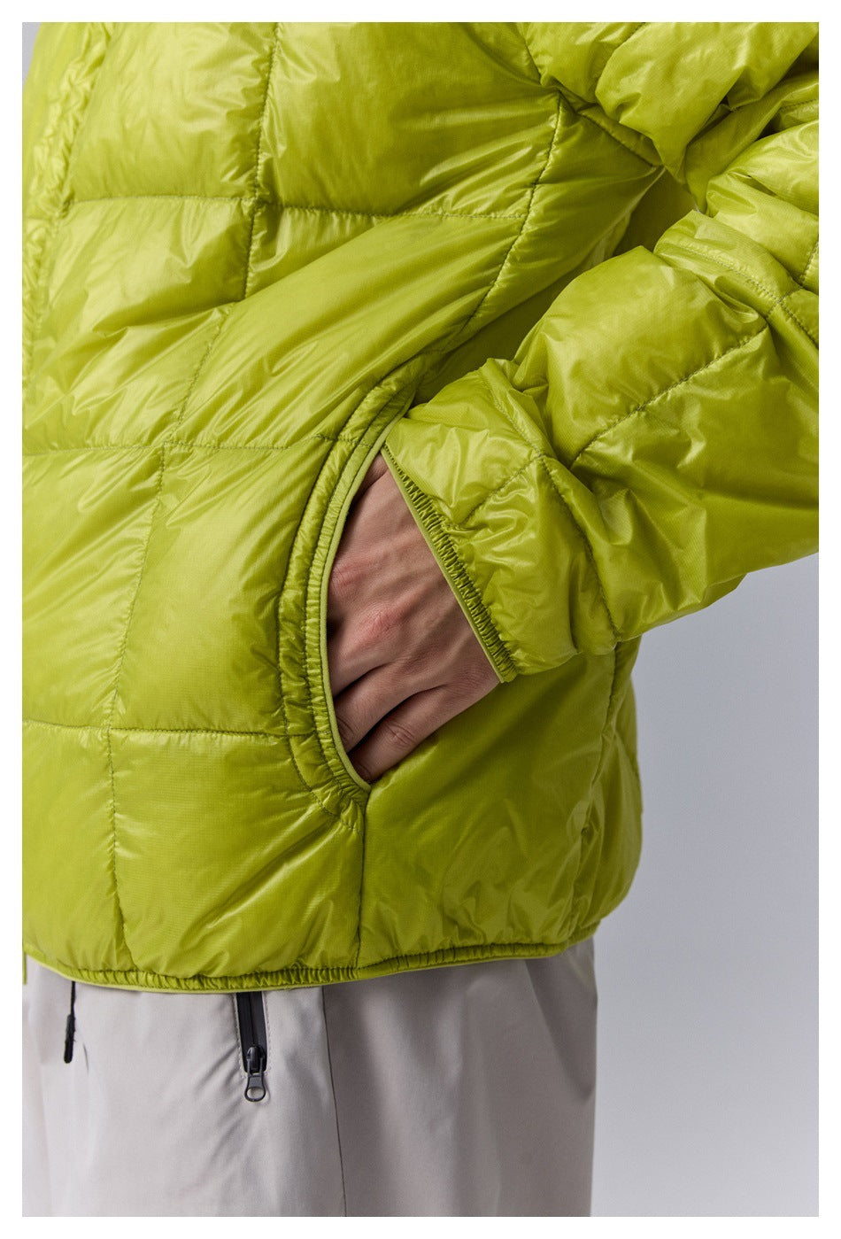 Close-up of the lime-green quilted jacket's elastic-trimmed side pocket and cuff.