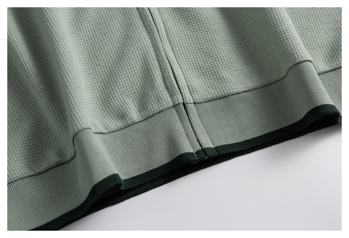 Close-up of the top's sage green hem with a wide ribbed band and dark green edge trim.