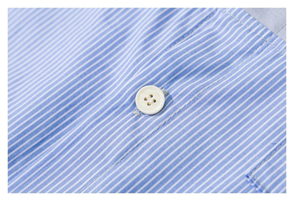 Close-up of a cream button on blue-and-white striped shirt fabric.