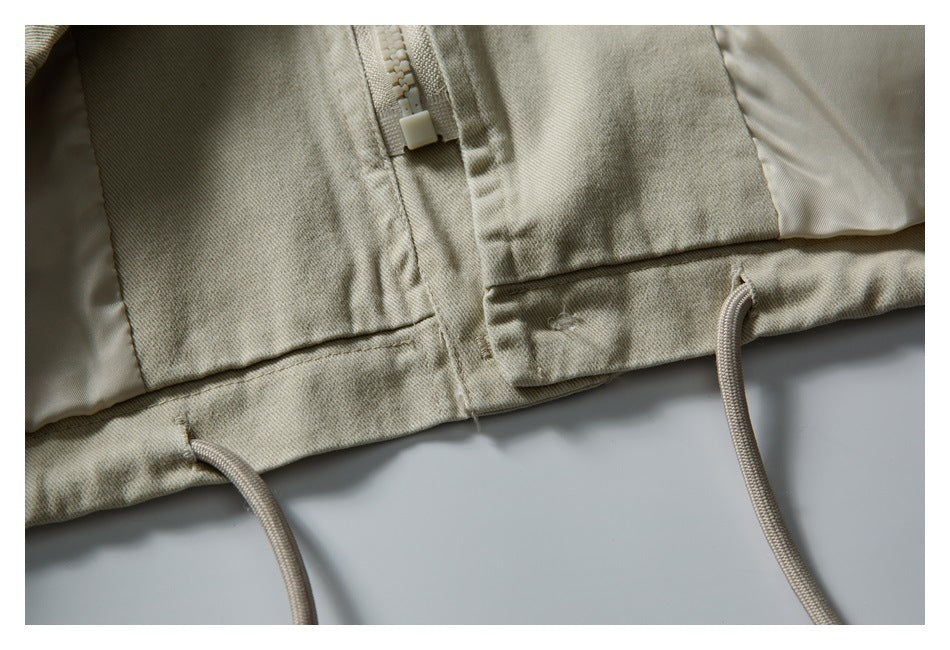 Close-up of the jacket hem with a zipper, stitched panels, and hanging drawcords.