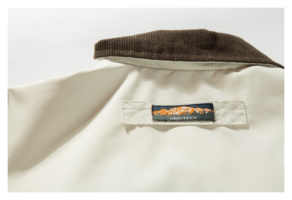 Close-up of an ivory garment collar with a brown ribbed section and a small sewn mountain-logo label.