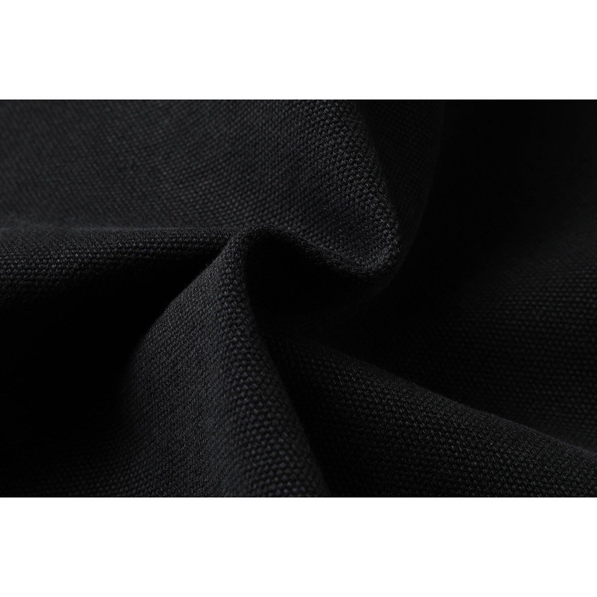 Extreme close-up of the black jacket's textured fabric, folded to show its surface.