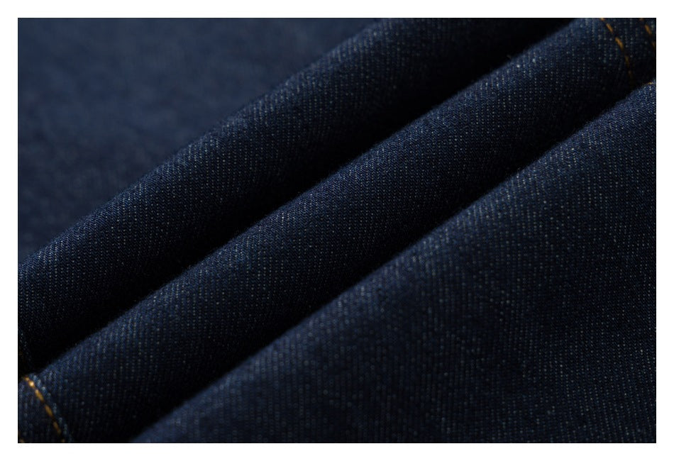 Macro view of dark indigo denim folded to show its fine diagonal weave and subtle texture.