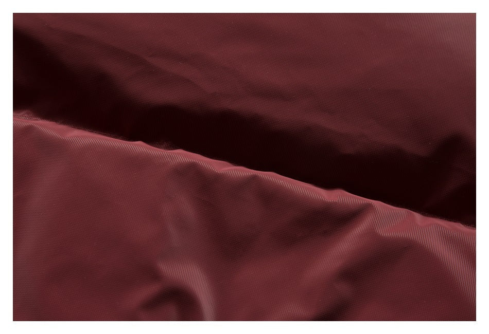 Close-up of burgundy jacket fabric with a stitched seam and soft folds.