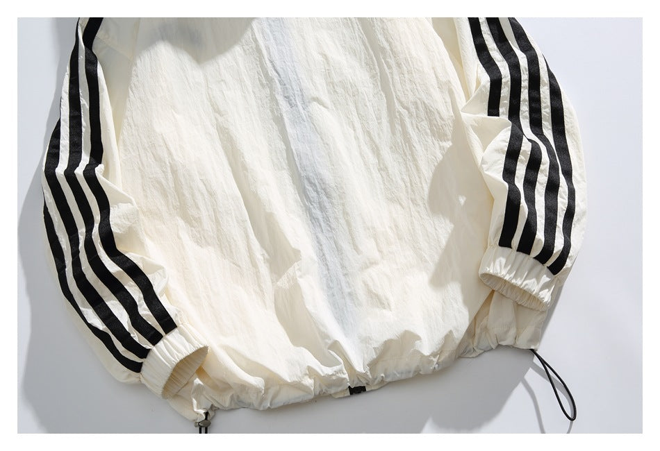 Cropped back view of an off-white jacket with black triple-striped sleeves, elastic cuffs, and a drawcord hem.