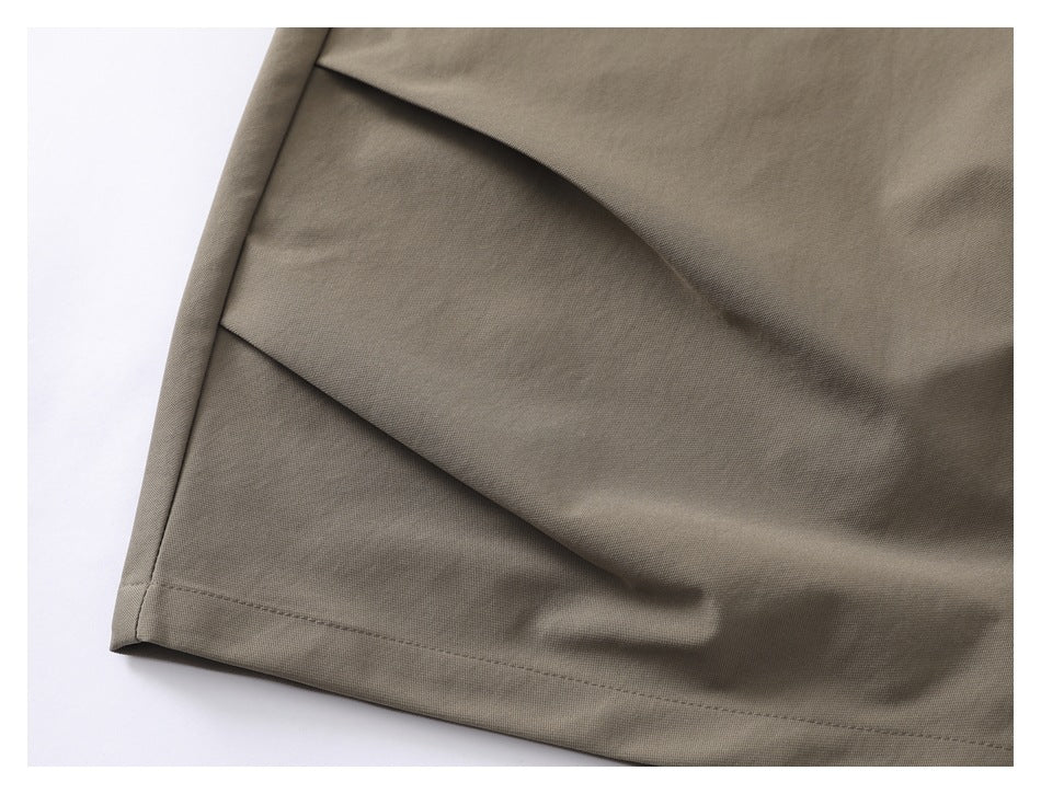 Close-up of the taupe trouser leg with a diagonal fabric panel and stitched hem.