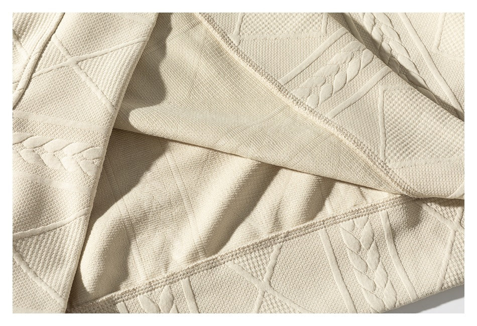 Close-up of the cream sweater's folded fabric and stitched edge, showing the patterned knit from inside and out.