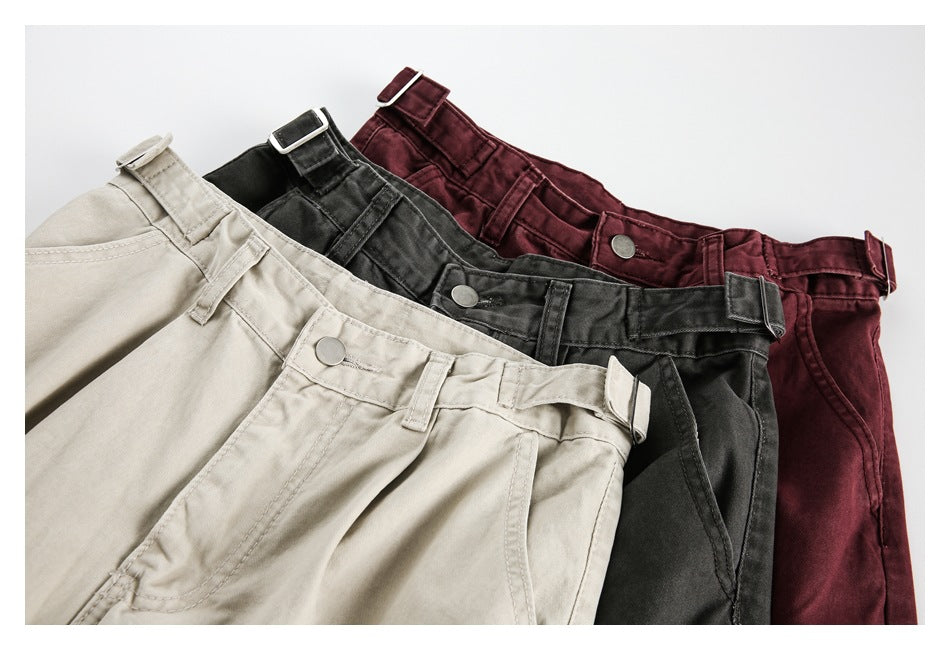 Three pairs of trousers in beige, charcoal, and burgundy, arranged to show their waistbands, buttons, and adjustable side