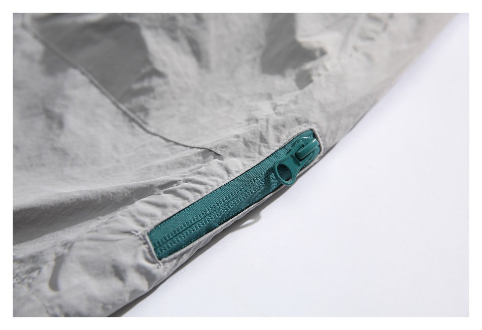 Detail of the teal zipper and pull on the hem of light gray shorts.