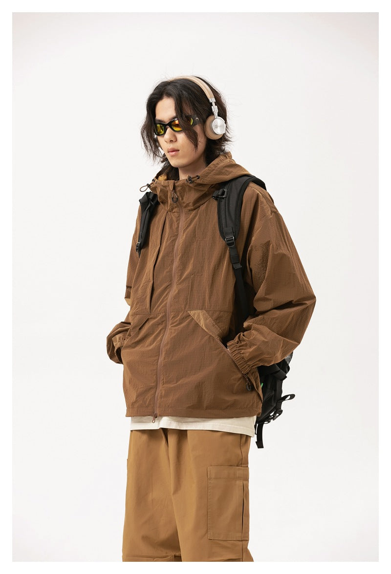 Model wearing a brown hooded zip jacket with front pockets, shown from a three-quarter angle.