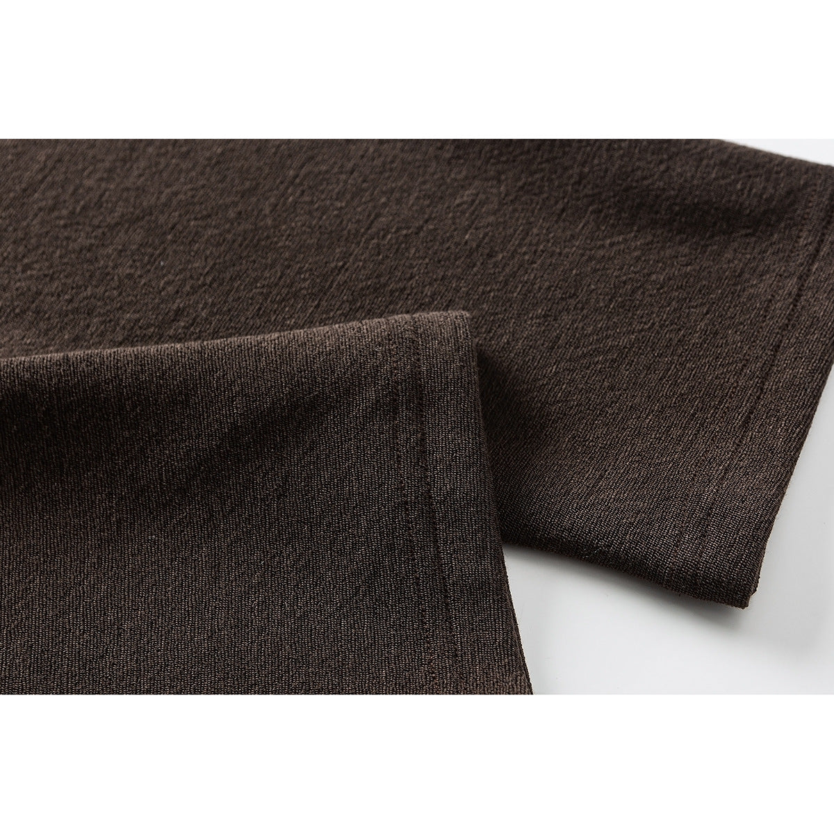 Close-up of dark brown fabric folded to show its fine textured knit.