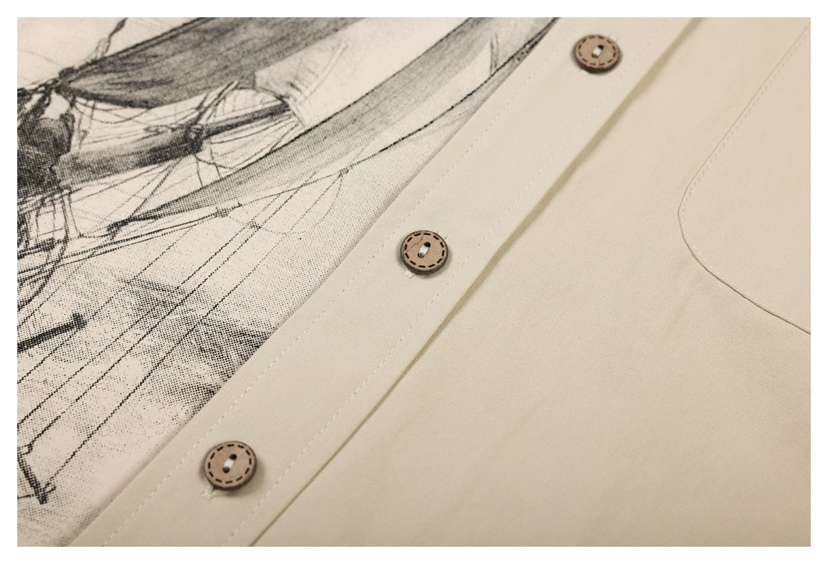 Close-up of a beige shirt placket with three brown buttons beside a black ship illustration print.