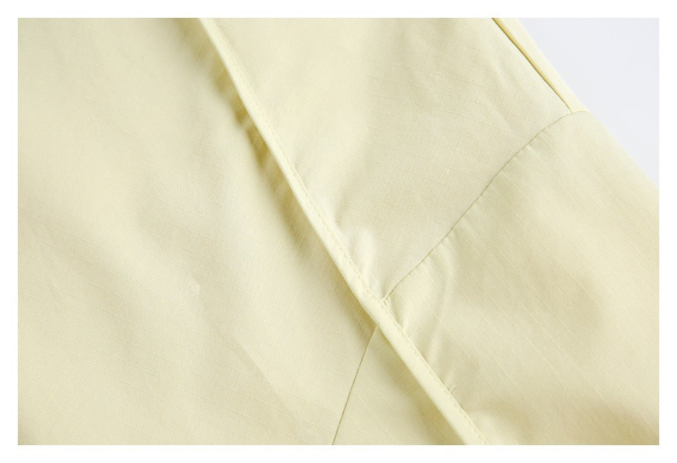 Close-up of pale yellow fabric with a curved stitched seam and narrow bound edge.