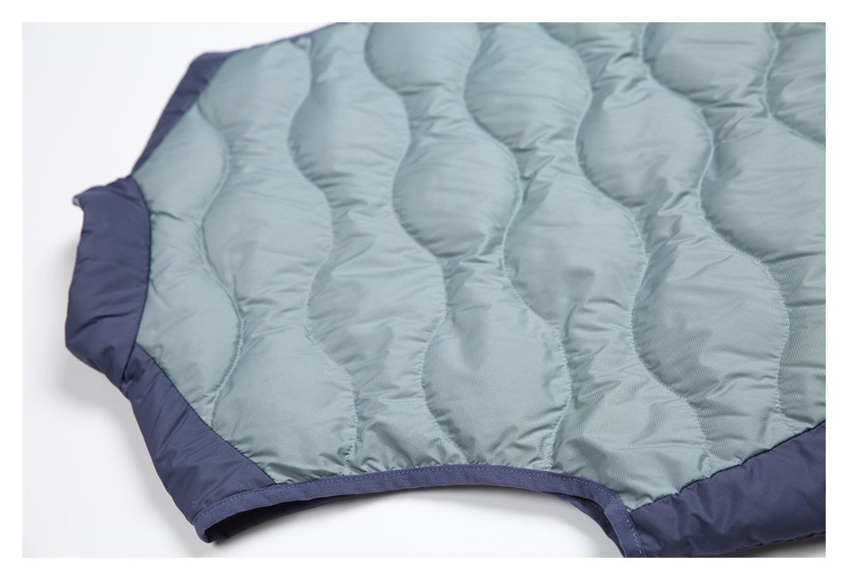 Close-up of a sage-green quilted padded panel with a curved dark navy border and bound opening.