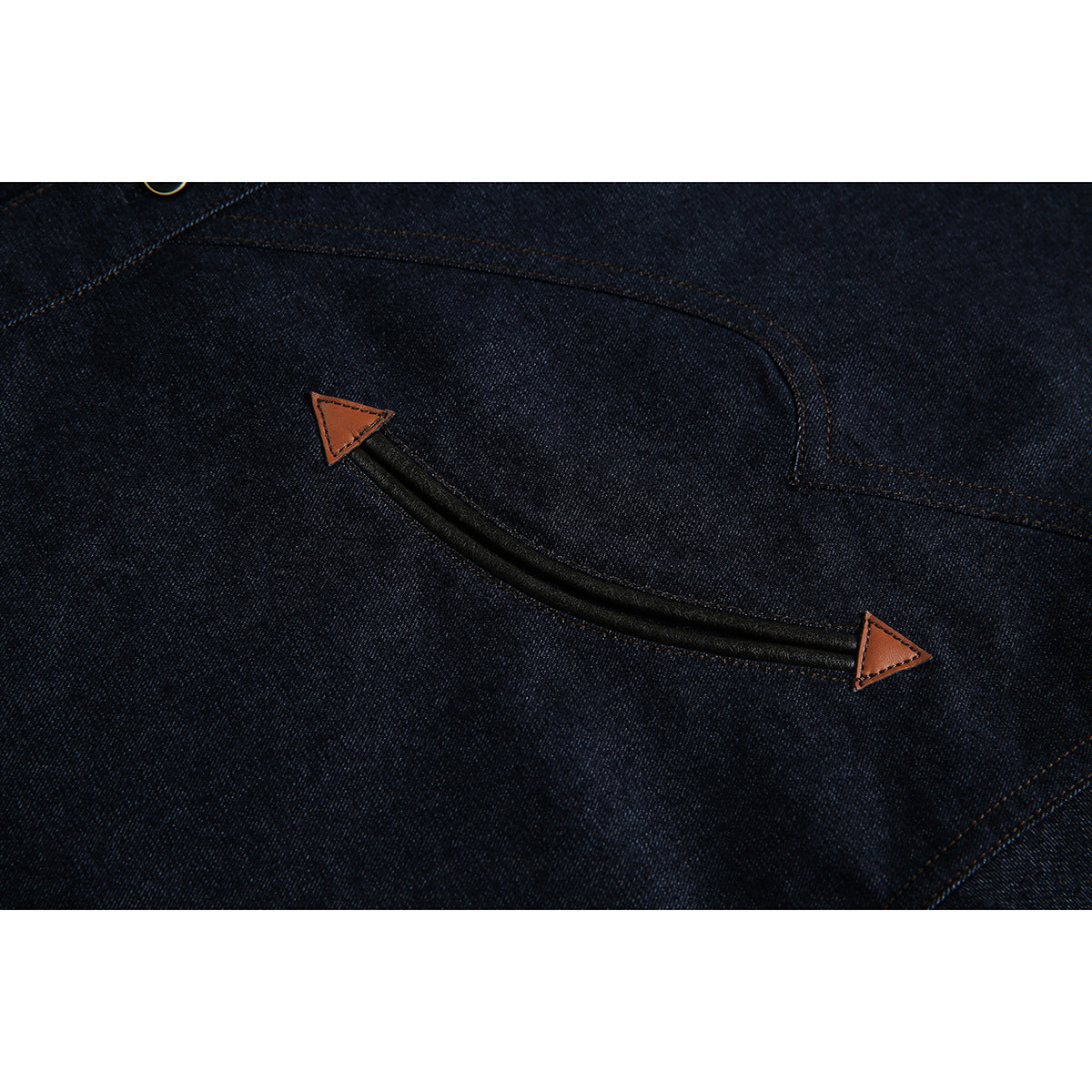 Close-up of dark indigo denim with a curved black trim detail ending in two brown triangular tabs.