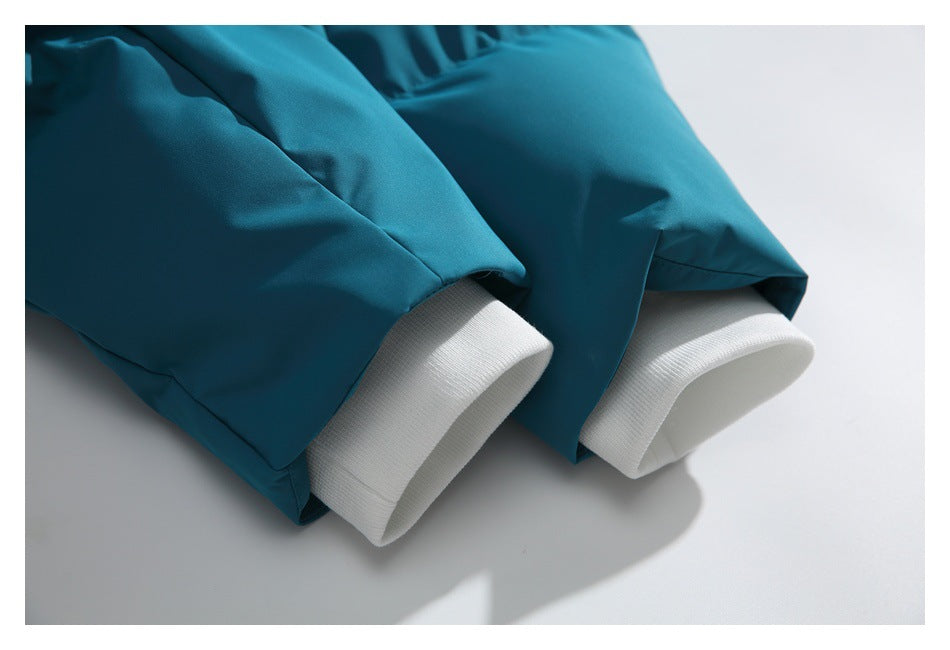 Close-up of teal jacket sleeves with wide white ribbed cuffs.