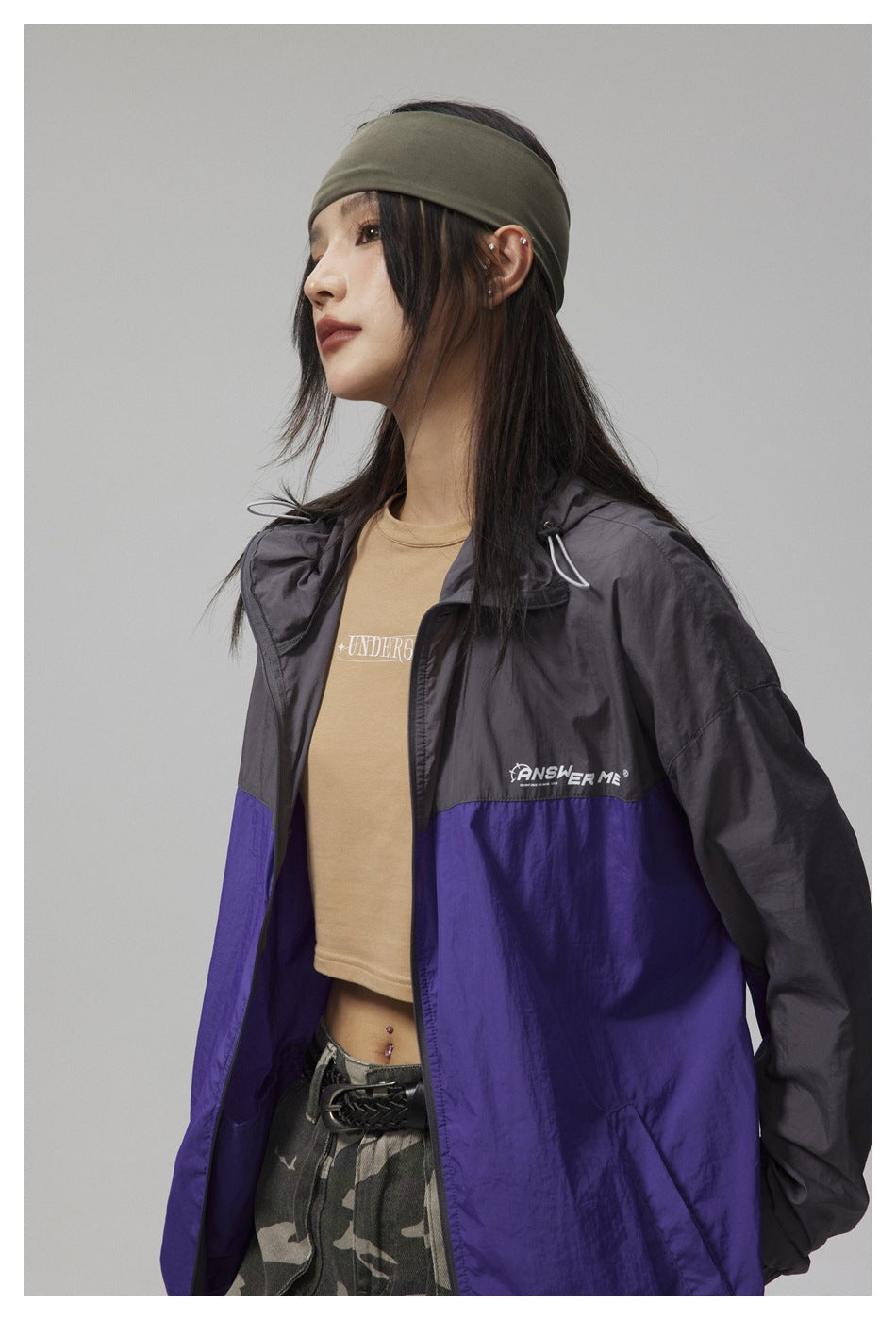 Model in a charcoal and purple color-block hooded jacket, shown from the side with the jacket open.