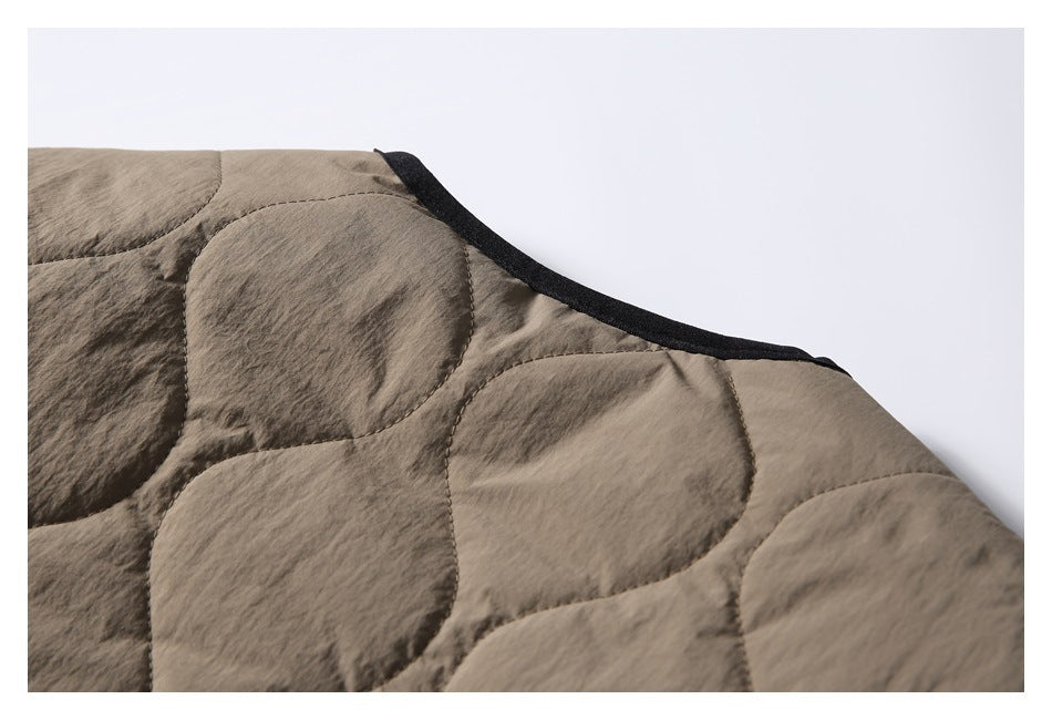 Close-up of the taupe jacket’s quilted shoulder and black-trimmed neckline.