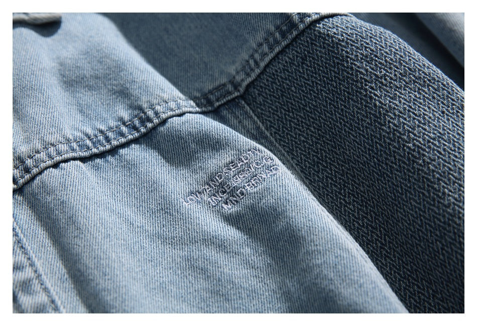 Close-up of light blue denim with contrast stitching, darker patterned denim, and small embroidered text.