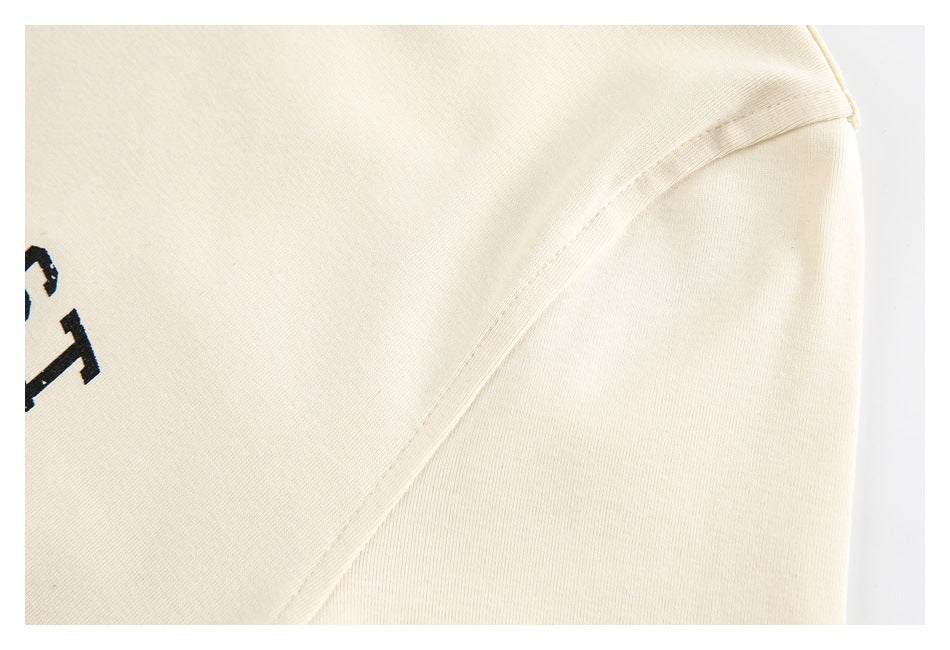 Close-up of the cream T-shirt's shoulder seam and sleeve construction.