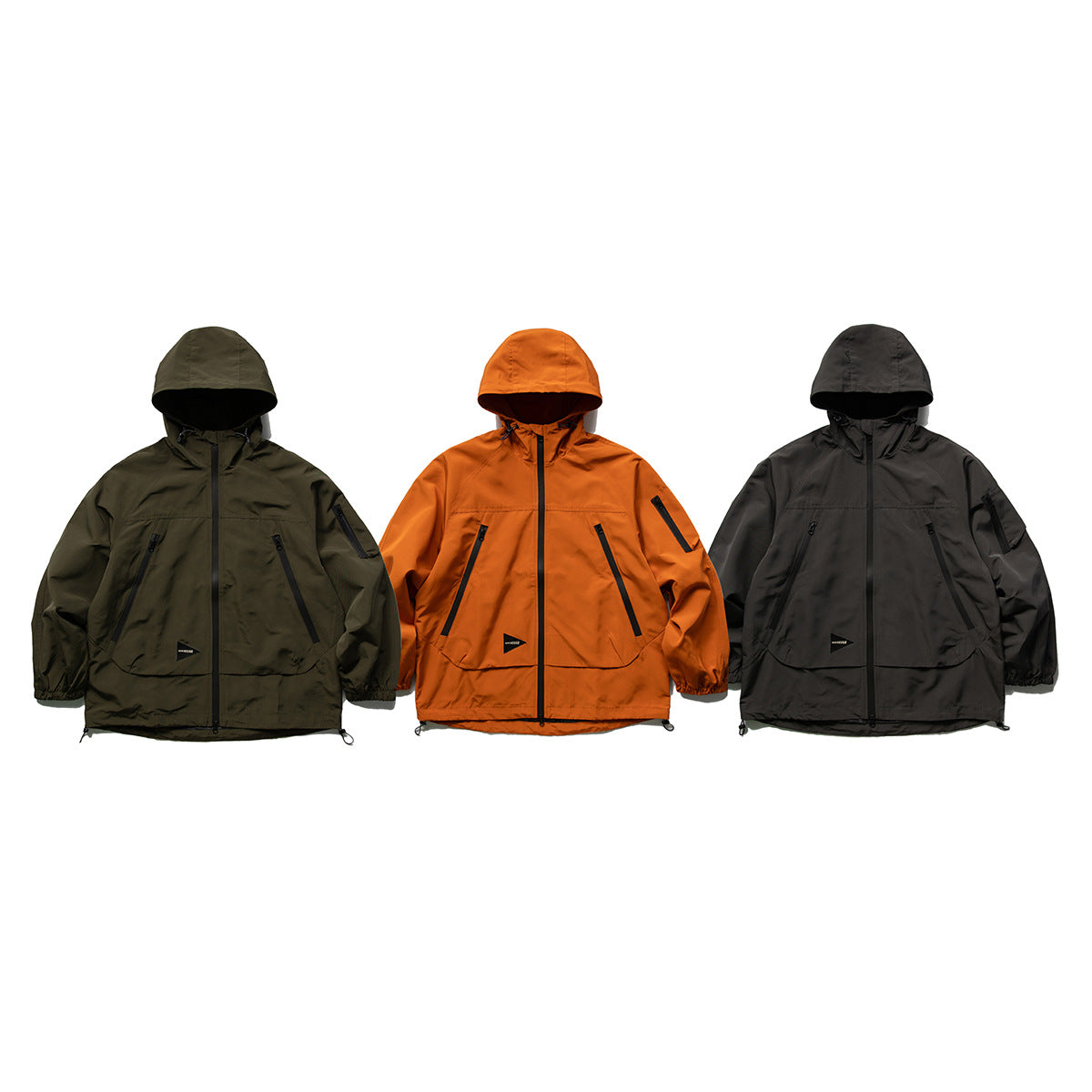Three hooded jackets shown from the front in olive, rust orange and charcoal, with zip pockets.