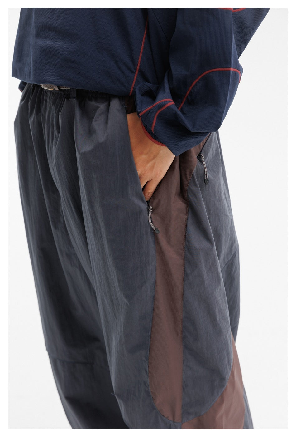 Close-up of the trousers' elastic waist and brown side panel with zip pockets and pull tabs.