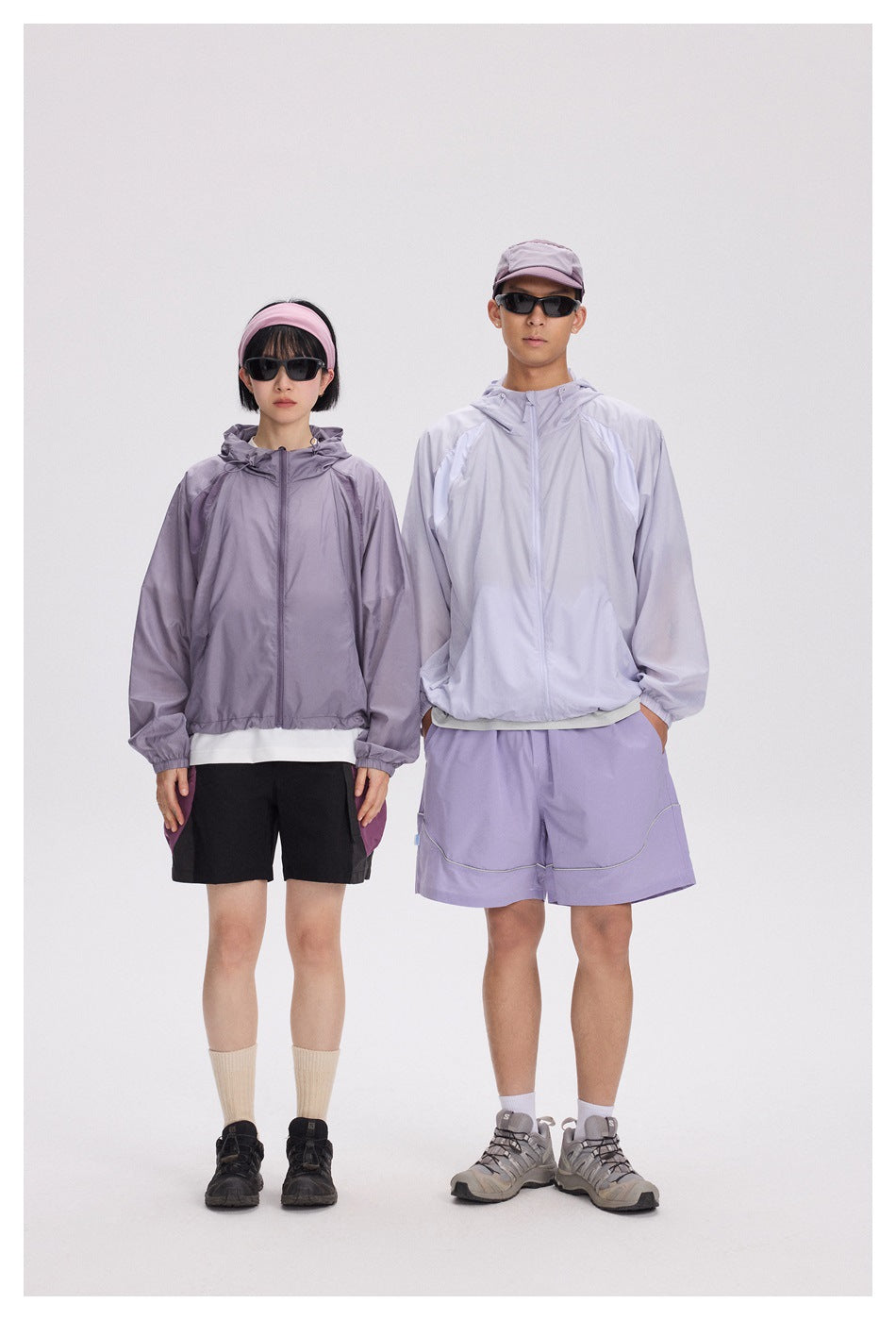 Two models wearing lavender hooded jackets; one wears black shorts and the other lavender shorts.