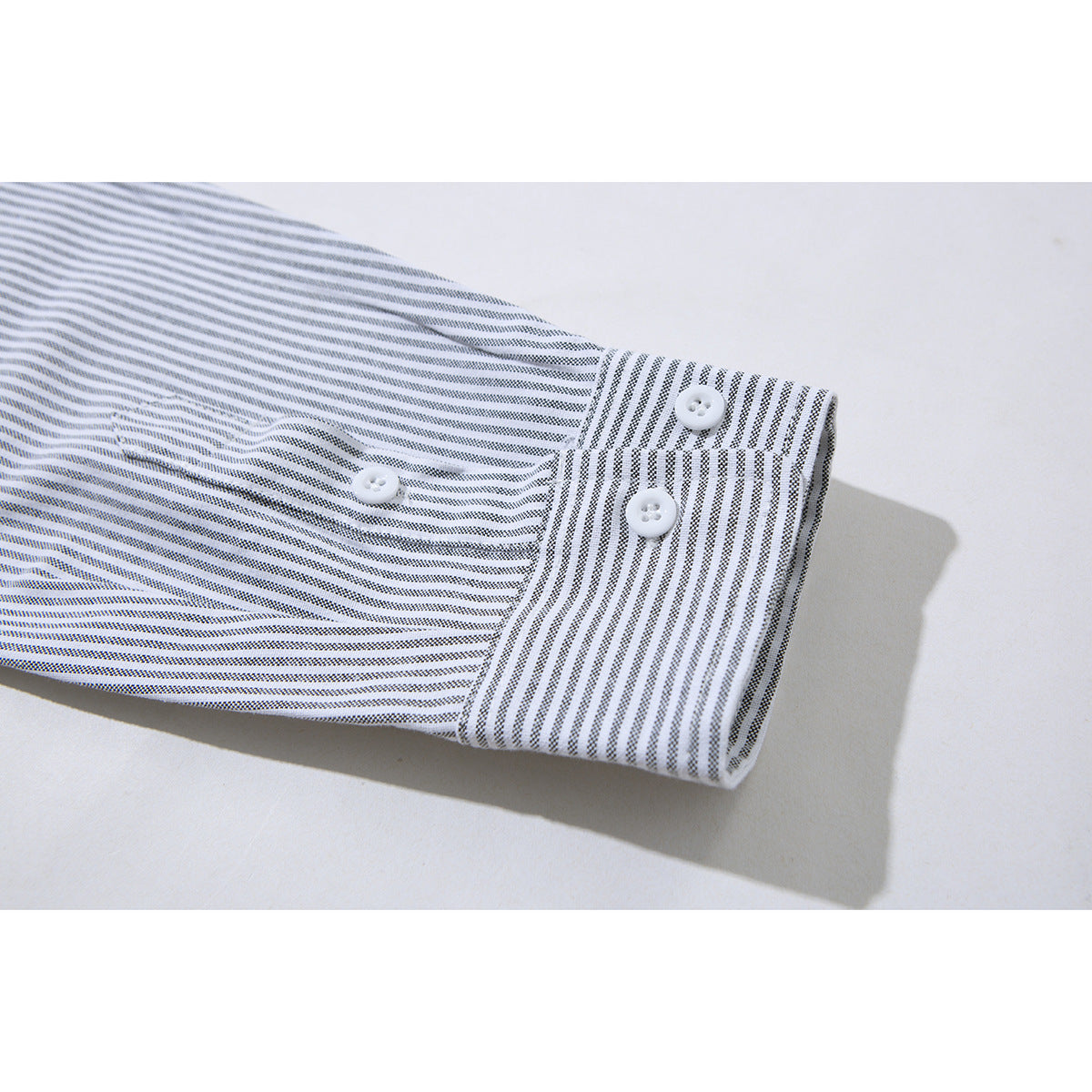 Close-up of a gray-and-white striped shirt sleeve and buttoned cuff.