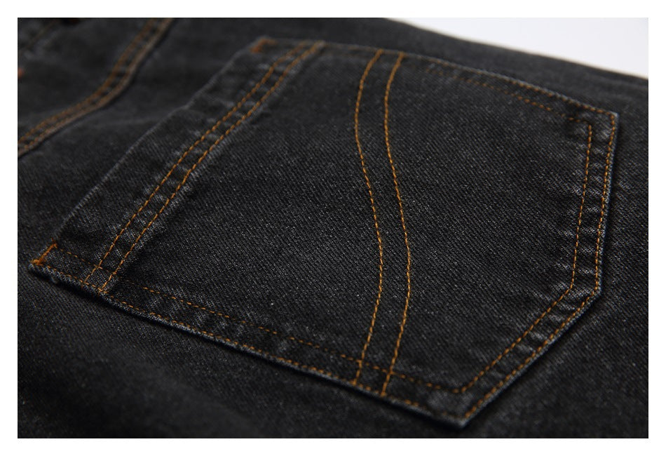Close-up of a back pocket on dark charcoal jeans, with curved brown contrast stitching.