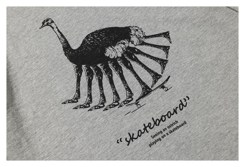 Close-up of a heather gray T-shirt printed with a black ostrich riding a skateboard and English text.