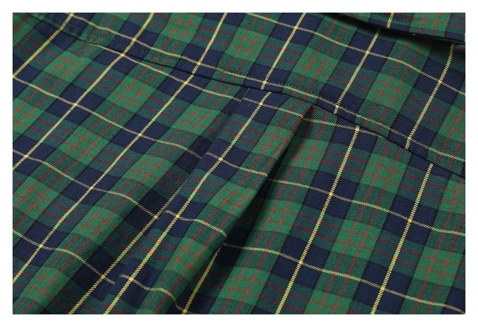 Close-up of green and navy plaid fabric with red and yellow lines and a curved stitched seam.
