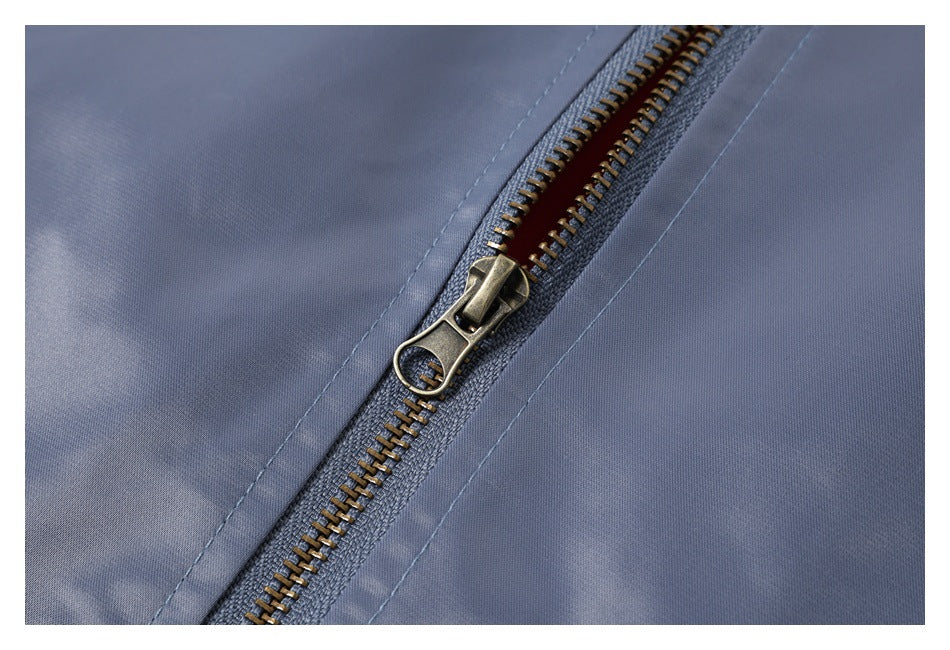 Close-up of a brass-toned zipper and stitching on slate-blue garment fabric.