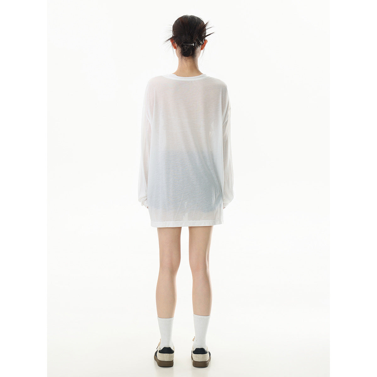Back view of a model wearing an oversized, sheer white long-sleeve tee with a plain back.