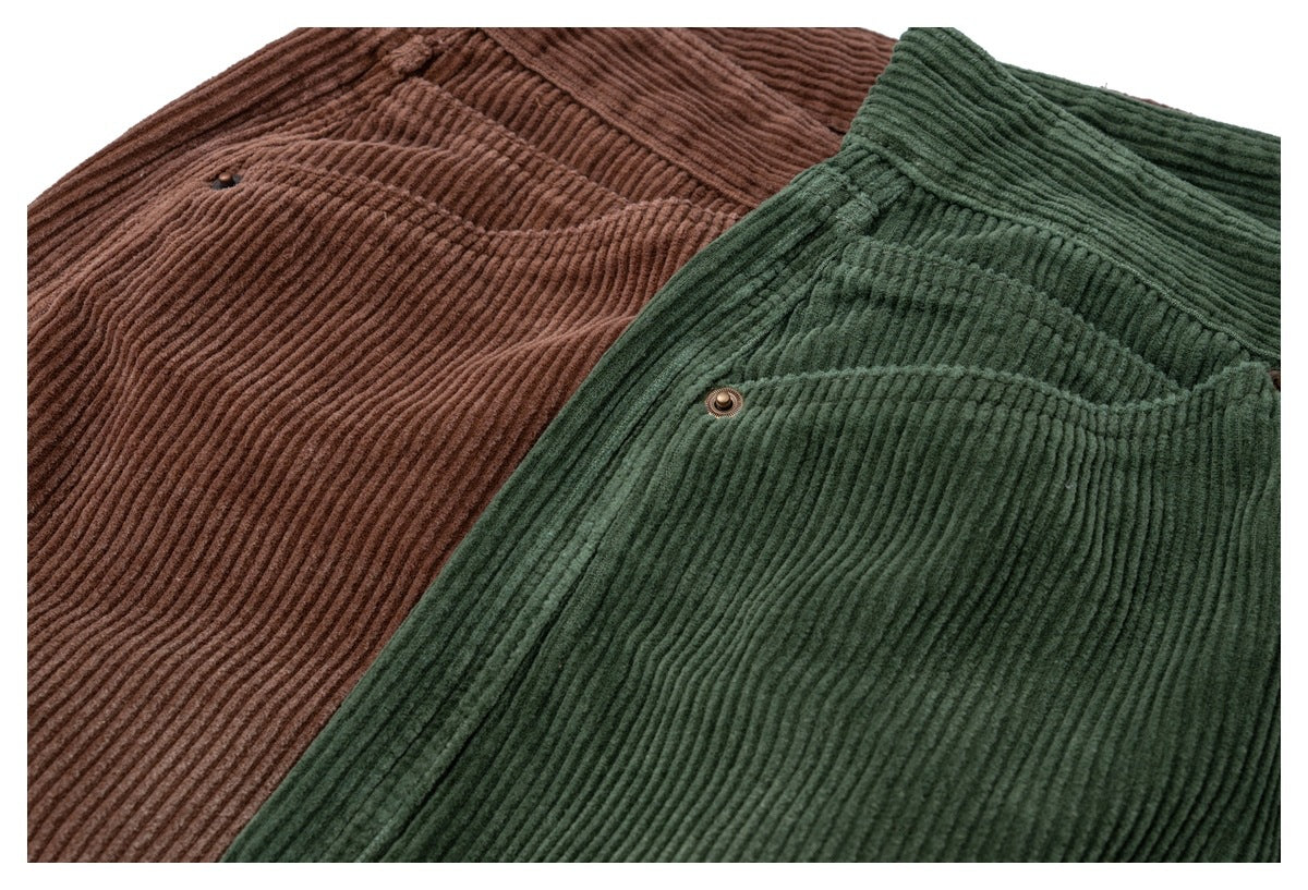 Close-up of brown and dark green corduroy trousers showing ribbed fabric, waistbands, and front pockets.