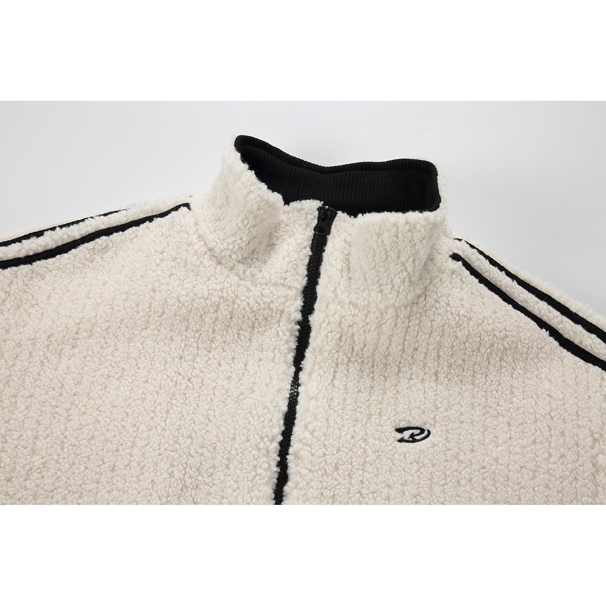 Close-up of an ivory textured zip jacket with a black stand collar, center zipper, sleeve stripes and small chest emblem.