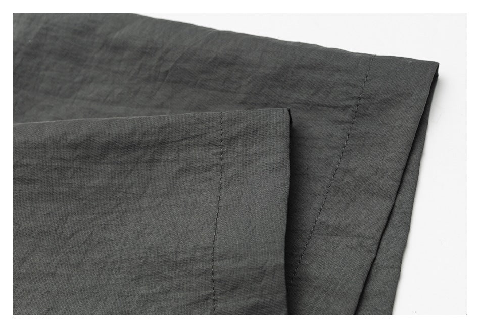 Close-up of charcoal gray fabric layers with a straight stitched seam and folded edge.