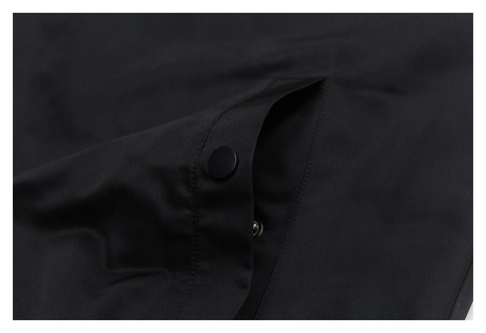 Close-up of a black garment's snap-button fastening and stitched placket.