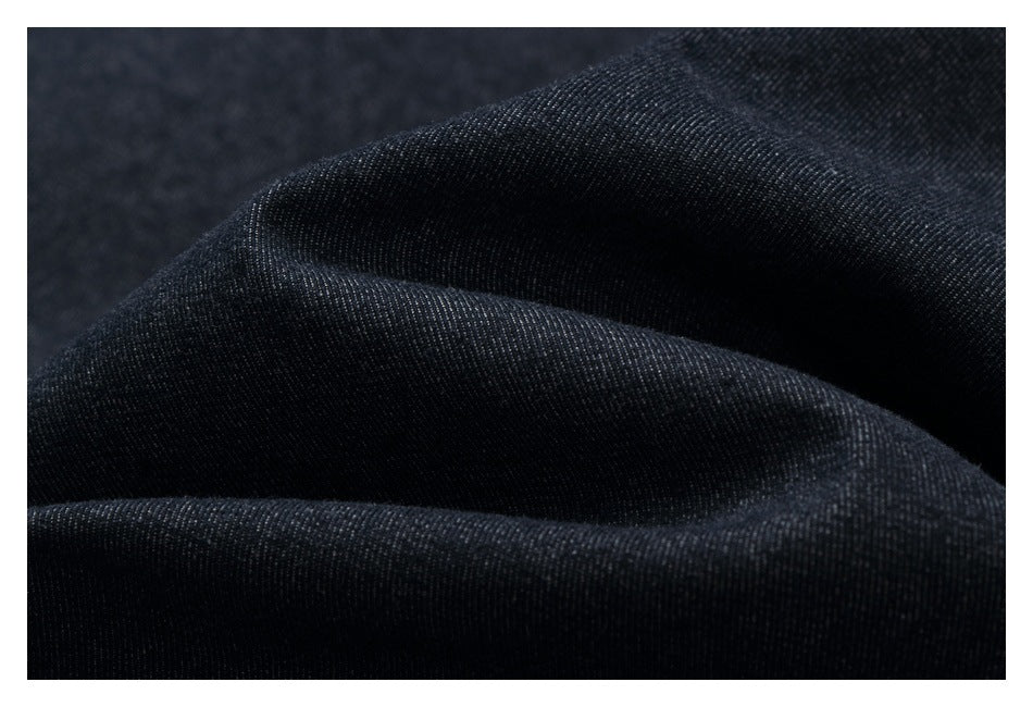 Close-up of dark indigo fabric draped in folds, showing its fine diagonal texture.