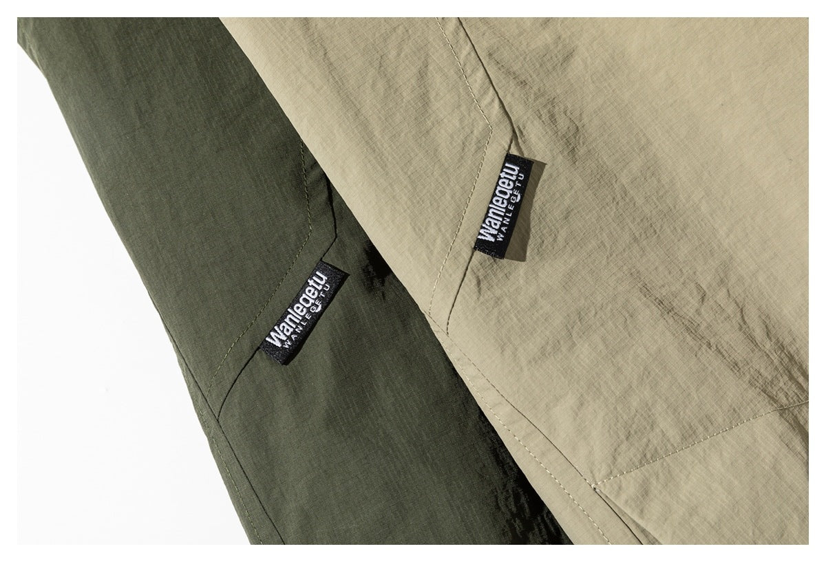 Close-up of sewn brand tabs on olive and khaki jacket sleeves, with stitching and fabric texture visible.
