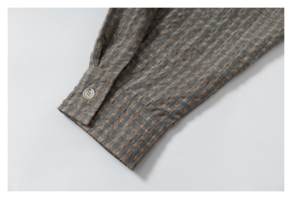 Close-up of a buttoned cuff on a gray-brown plaid sleeve.