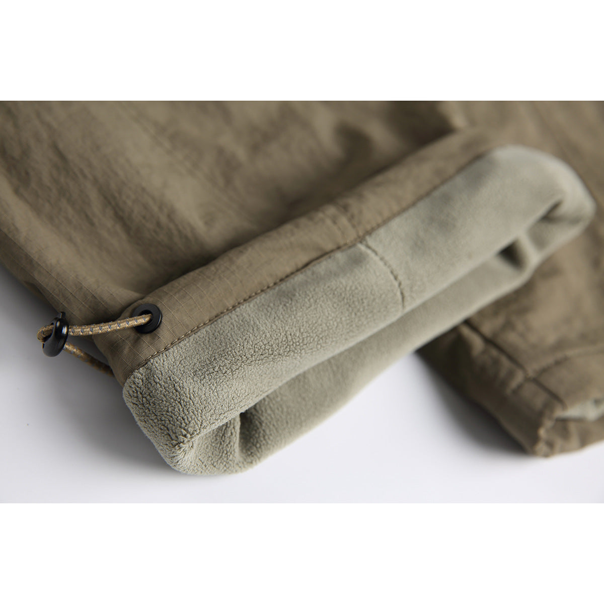 Close-up of a pant leg hem with a braided drawcord adjuster and fuzzy light-gray lining.