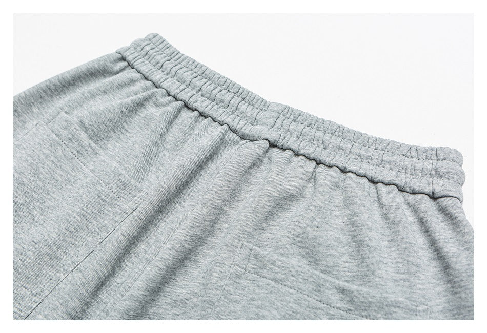 Close-up of heather gray shorts with a gathered elastic waistband and pocket seam.