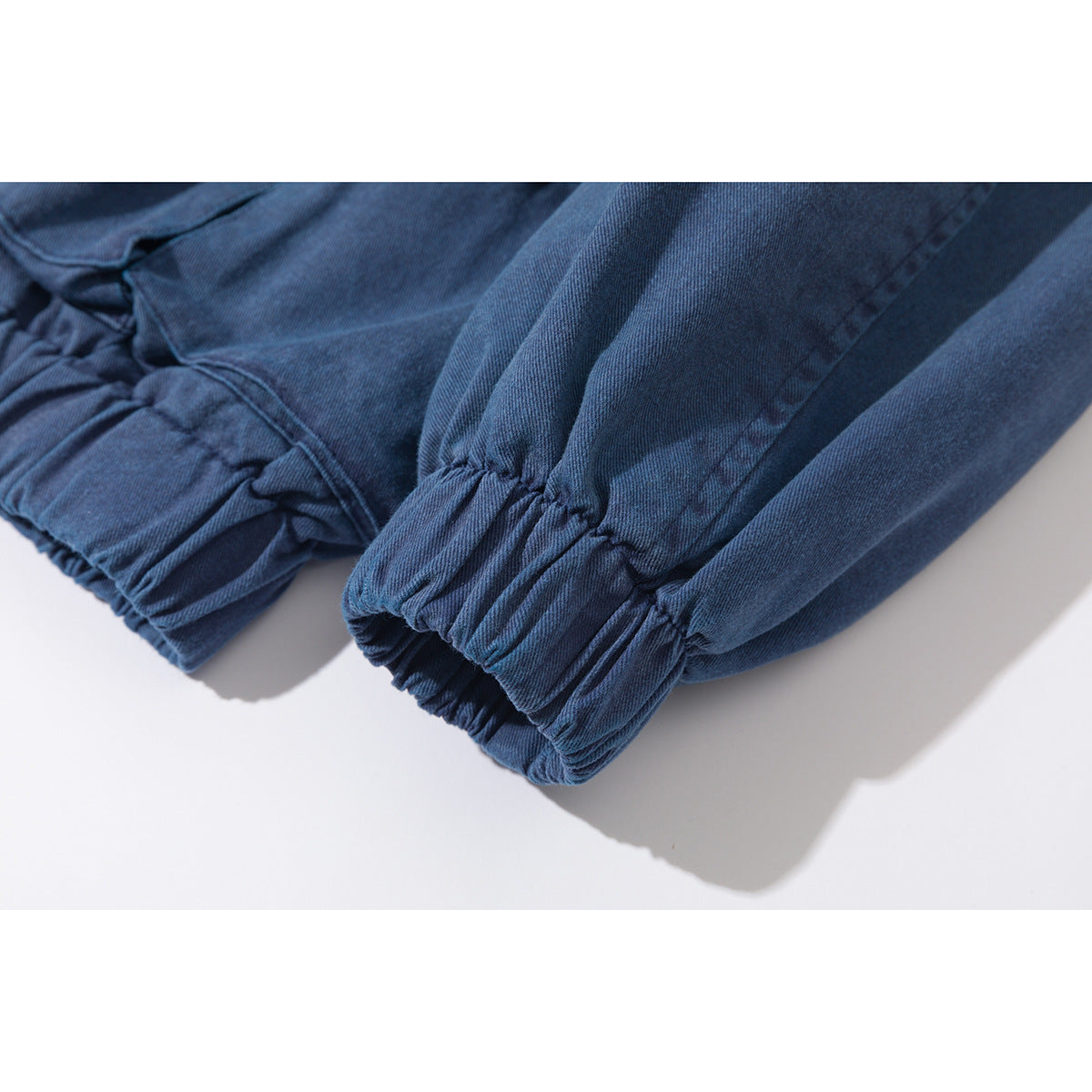 Close-up of a blue jacket sleeve ending in a gathered elastic cuff.