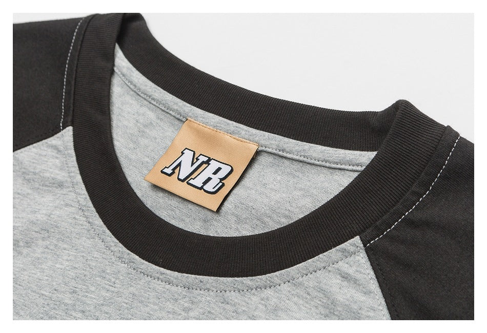 Close-up of a gray T-shirt neckline with black trim and a tan NB neck label.