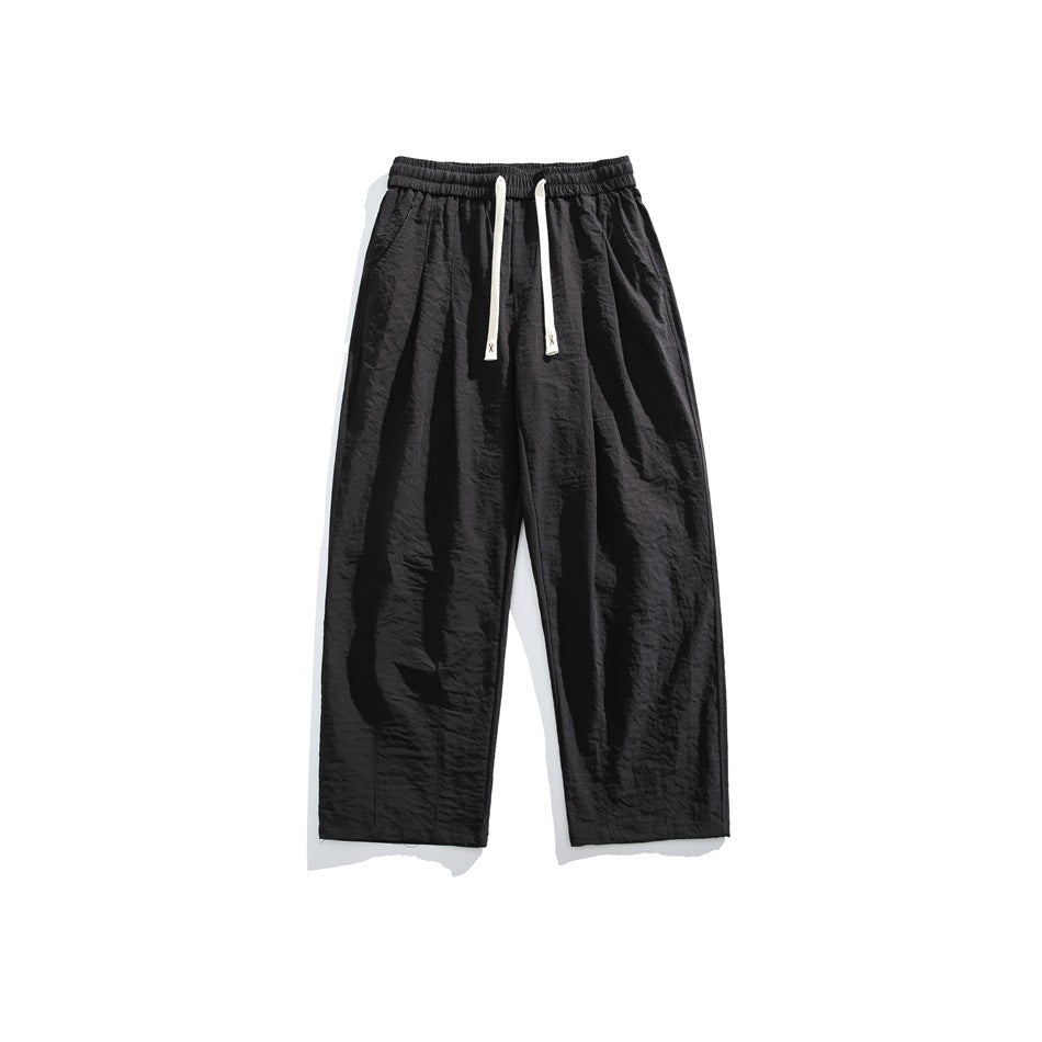 Black wide-leg drawstring pants with elastic waistband and front pleats, flat lay front view