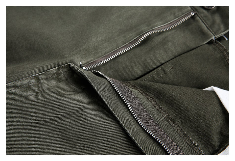 Close-up of olive-gray trousers showing the metal zipper fly and stitched front panels.