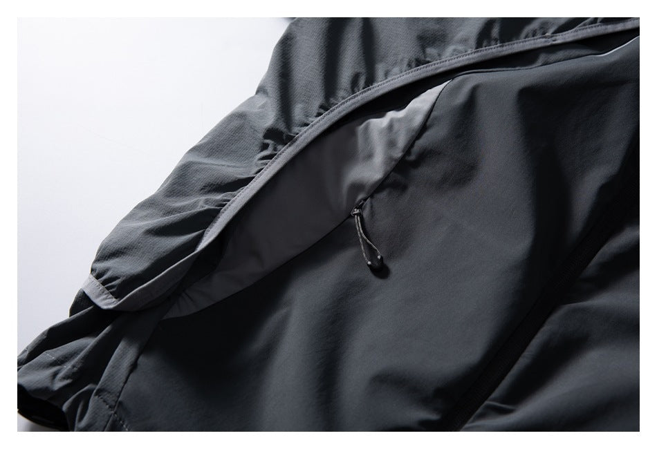 Close-up of a dark charcoal jacket showing a zippered pocket and hood edge.