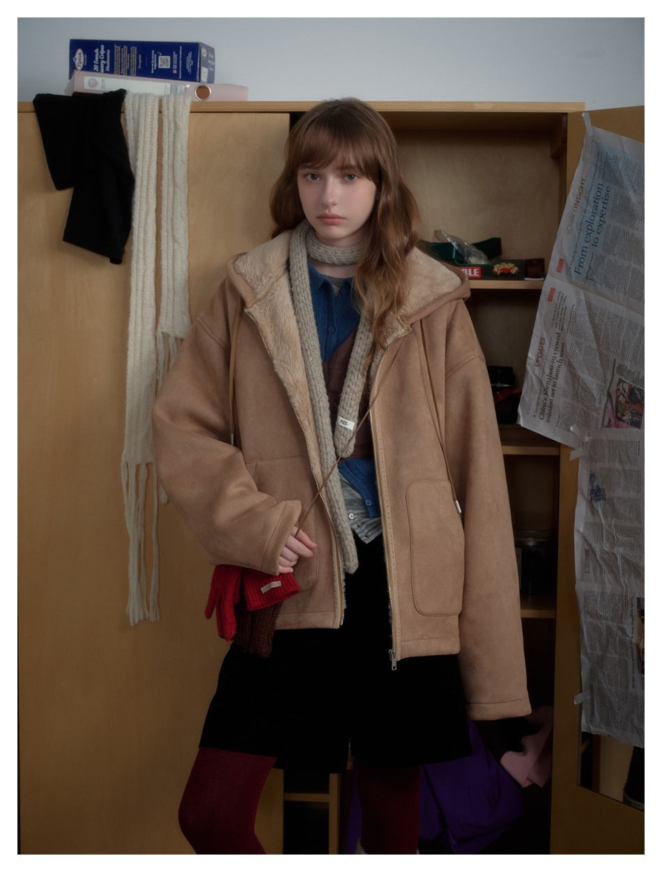 Three-quarter view of a model in a tan shearling-lined jacket over layered knitwear and a black skirt.