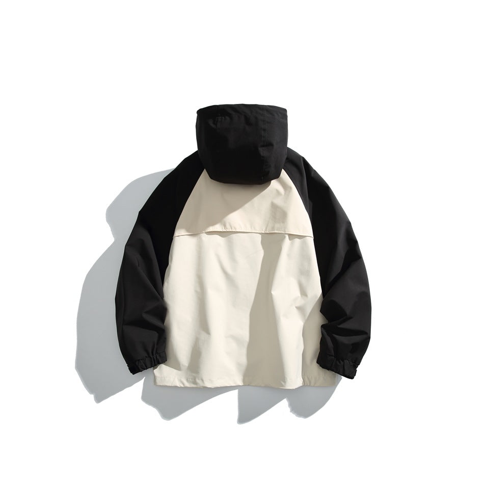 Back view of a cream-and-black hooded jacket laid flat, with a cream upper-back flap and black sleeves.